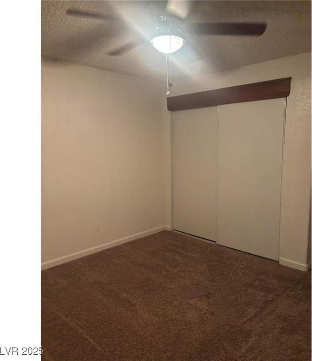 empty room featuring a textured ceiling, carpet floors, baseboards, and a ceiling fan