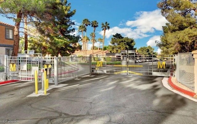 view of road with a gate, a gated entry, and curbs