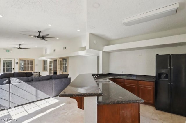kitchen featuring black fridge with ice dispenser, a sink, ceiling fan, light tile patterned flooring, and a kitchen bar