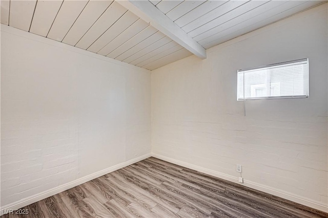 spare room with wooden ceiling, baseboards, vaulted ceiling with beams, and wood finished floors