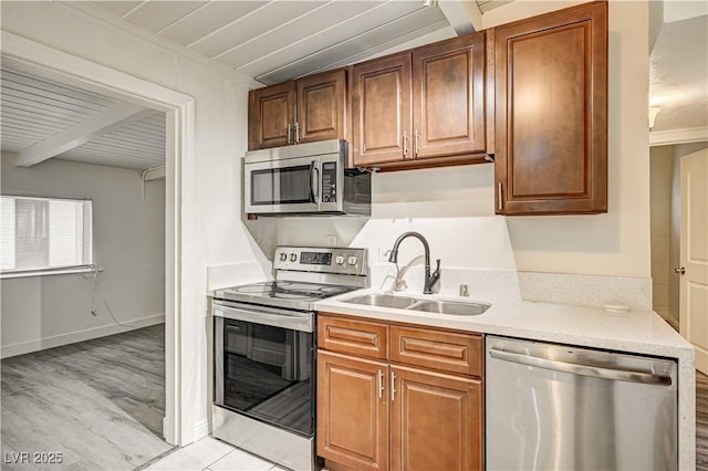 kitchen with light countertops, appliances with stainless steel finishes, light wood-style floors, and a sink