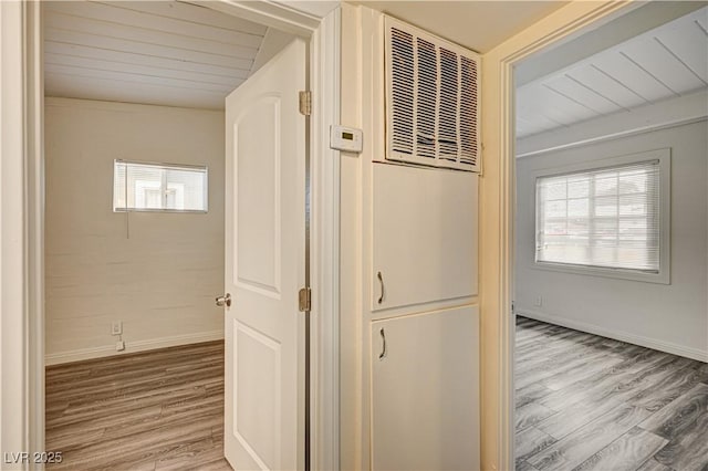 corridor featuring wooden ceiling, baseboards, and wood finished floors
