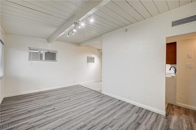 empty room featuring wood finished floors, beam ceiling, visible vents, baseboards, and wooden ceiling