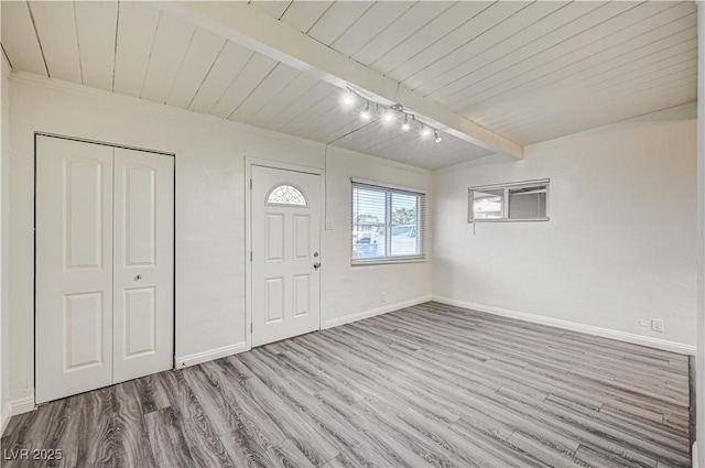 foyer featuring baseboards, beamed ceiling, track lighting, and wood finished floors