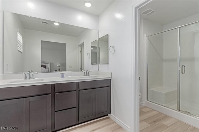 full bath featuring a sink, visible vents, and wood finished floors