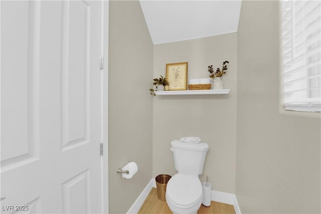 bathroom with toilet, baseboards, and wood finished floors