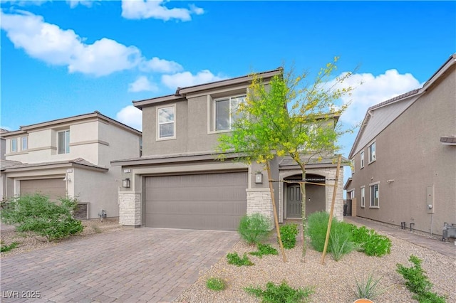 traditional home featuring a garage, stucco siding, and decorative driveway