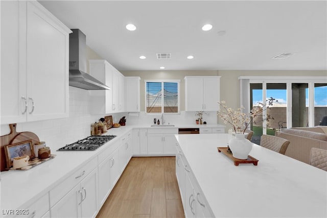 kitchen with recessed lighting, wall chimney exhaust hood, a healthy amount of sunlight, and stainless steel gas cooktop