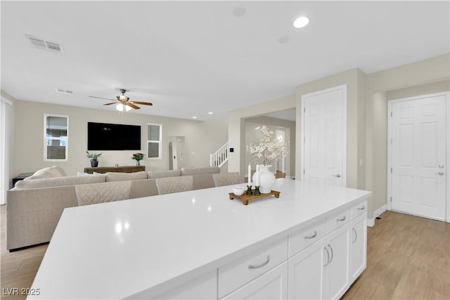 kitchen with ceiling fan, light wood finished floors, visible vents, and white cabinets