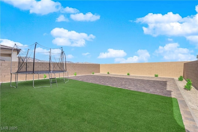 view of yard featuring a fenced backyard, a patio area, and a trampoline