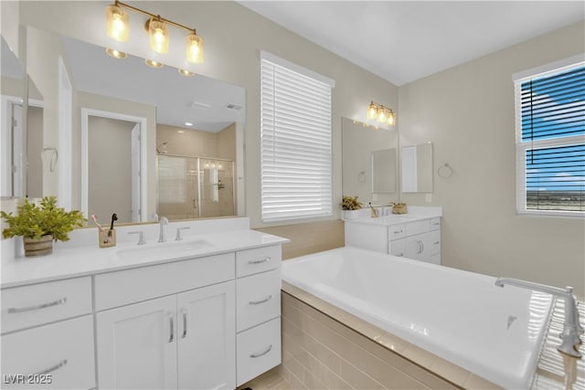 full bath featuring visible vents, a bath, a sink, a shower stall, and two vanities