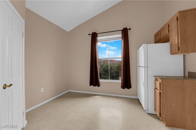 kitchen with freestanding refrigerator, lofted ceiling, and baseboards