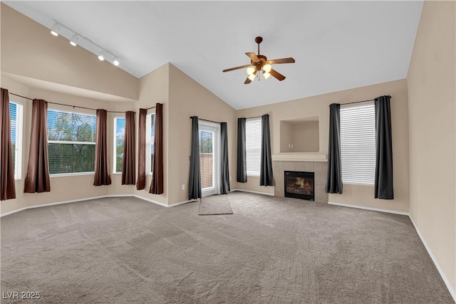 unfurnished living room with a ceiling fan, baseboards, rail lighting, vaulted ceiling, and carpet floors