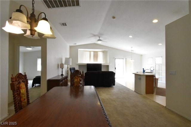 dining room with vaulted ceiling, light colored carpet, a ceiling fan, and visible vents