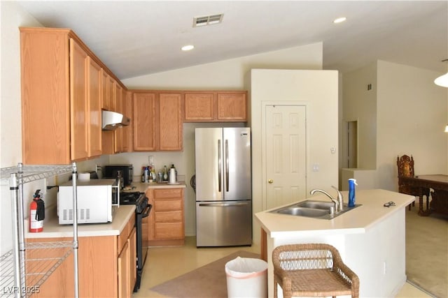 kitchen with a sink, freestanding refrigerator, visible vents, white microwave, and under cabinet range hood