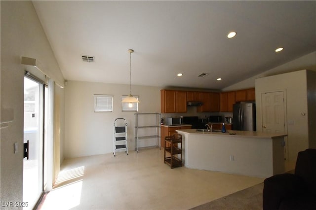 kitchen with freestanding refrigerator, brown cabinetry, visible vents, stainless steel microwave, and vaulted ceiling