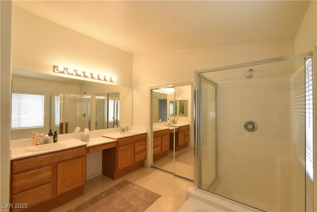 bathroom with double vanity, a shower stall, and a sink