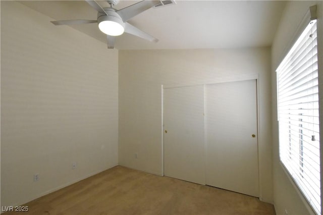 unfurnished bedroom featuring a closet, visible vents, ceiling fan, and light carpet