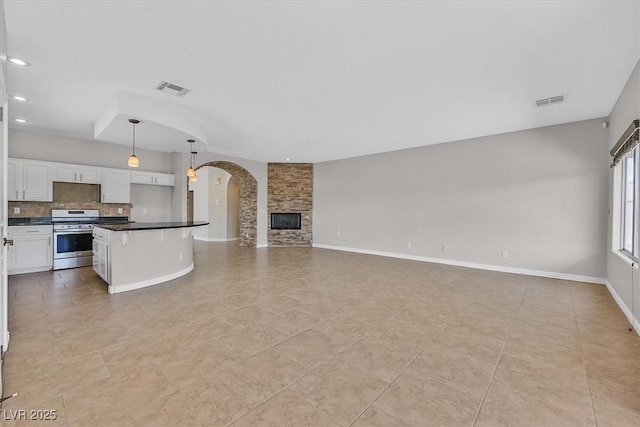unfurnished living room featuring arched walkways, light tile patterned floors, visible vents, and recessed lighting