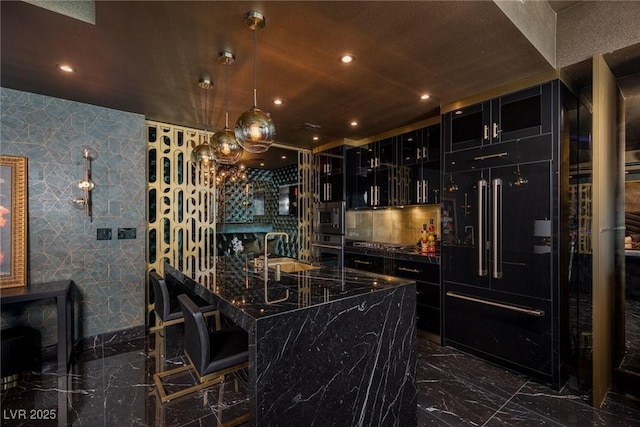 kitchen with dark cabinets, a breakfast bar area, a sink, black appliances, and marble finish floor