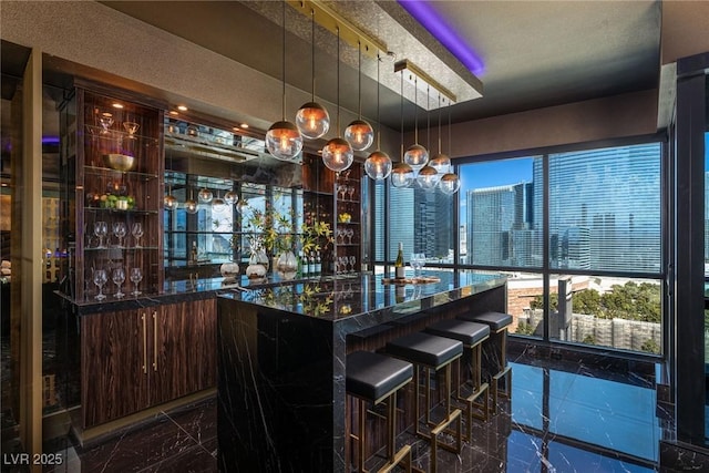 bar featuring hanging light fixtures, marble finish floor, and indoor wet bar