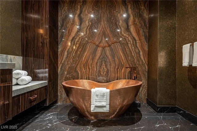 bathroom with a freestanding bath, marble finish floor, and vanity