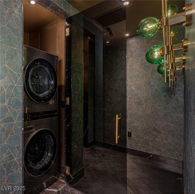 clothes washing area with laundry area, stacked washer / drying machine, and marble finish floor
