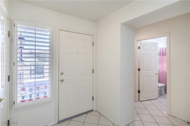 foyer entrance with light tile patterned floors and baseboards