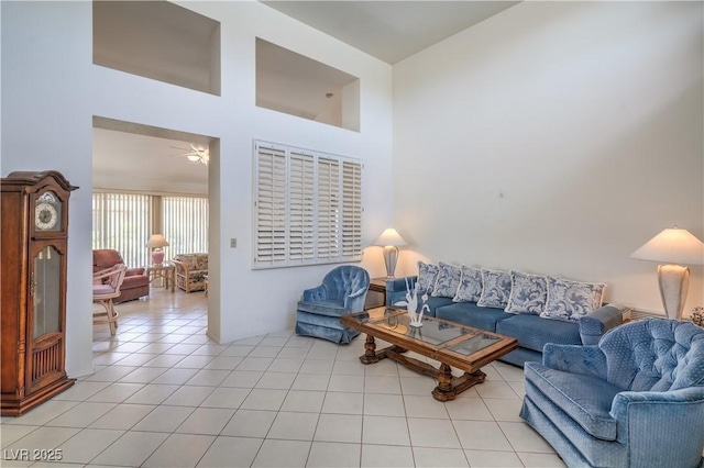 living room featuring ceiling fan, light tile patterned flooring, and a high ceiling