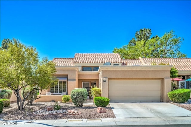 view of front of house featuring a tile roof, concrete driveway, an attached garage, and stucco siding