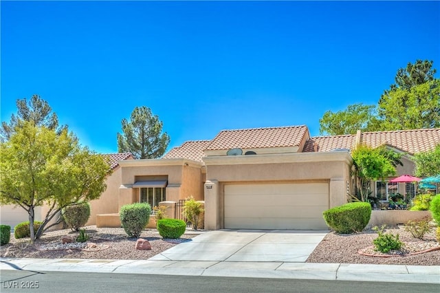 view of front facade with a tiled roof, stucco siding, driveway, and a garage