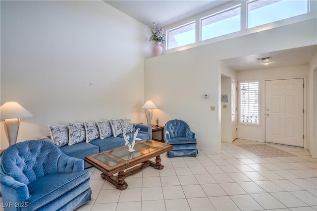 living area with vaulted ceiling, visible vents, light tile patterned flooring, and a healthy amount of sunlight