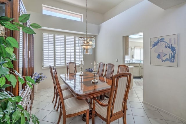 dining area featuring an inviting chandelier, light tile patterned floors, baseboards, and a high ceiling