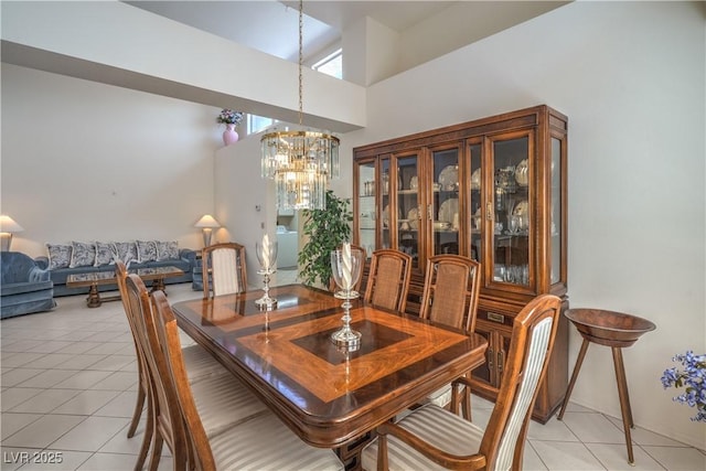 dining room with an inviting chandelier, light tile patterned flooring, and a high ceiling