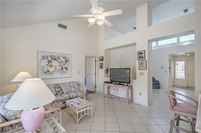 living room with a ceiling fan, visible vents, light tile patterned flooring, and high vaulted ceiling
