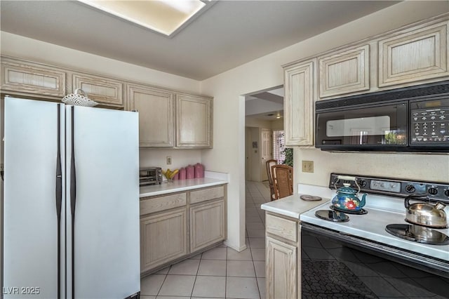kitchen with freestanding refrigerator, light tile patterned floors, electric range oven, black microwave, and light countertops