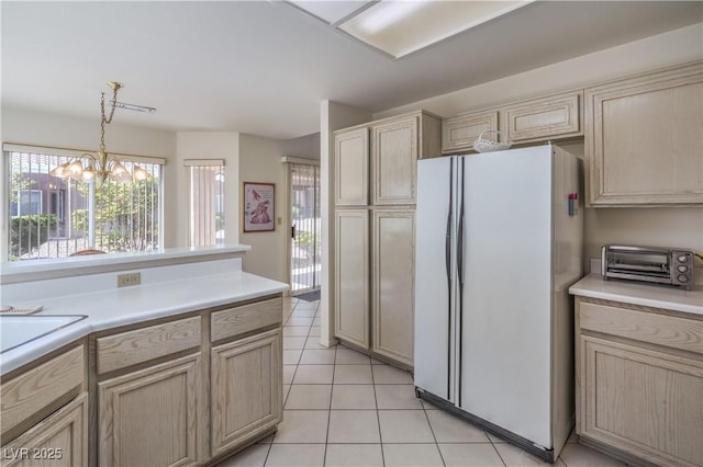 kitchen with freestanding refrigerator, a toaster, a chandelier, light countertops, and light tile patterned floors
