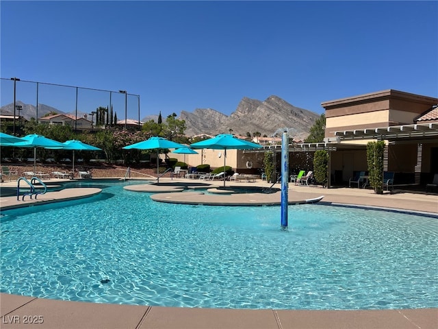 pool featuring fence, a patio area, and a mountain view