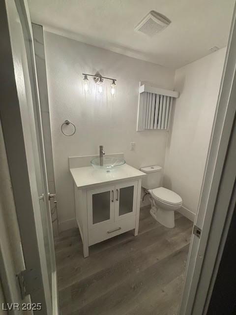bathroom featuring toilet, wood finished floors, visible vents, baseboards, and vanity