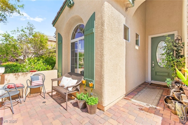 view of exterior entry with a patio area and stucco siding