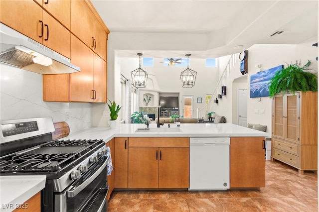 kitchen featuring a sink, a peninsula, dishwasher, under cabinet range hood, and stainless steel gas range