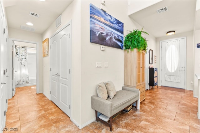 hall featuring light tile patterned floors, visible vents, and baseboards