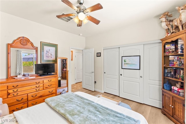 bedroom with a closet, light wood-style floors, and a ceiling fan