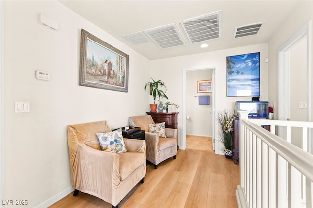 living area with light wood finished floors, visible vents, and baseboards