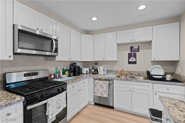 kitchen featuring light wood-style floors, white cabinetry, stainless steel appliances, and a sink