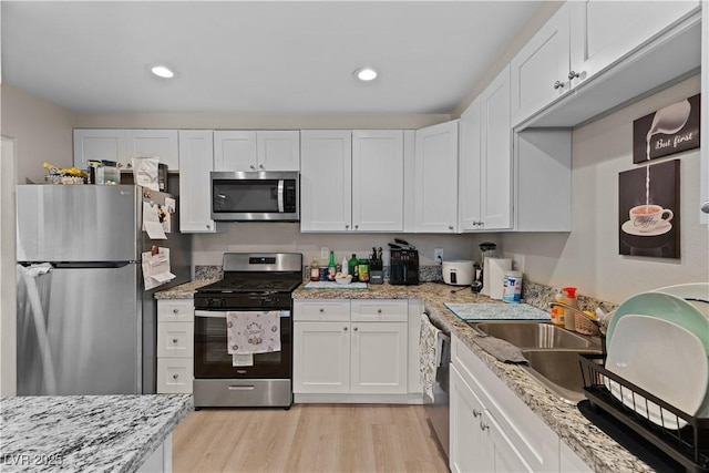 kitchen featuring a sink, white cabinets, appliances with stainless steel finishes, and light wood-style flooring