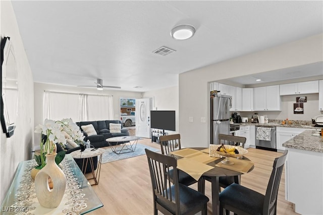 dining area with a ceiling fan, light wood-style flooring, and visible vents
