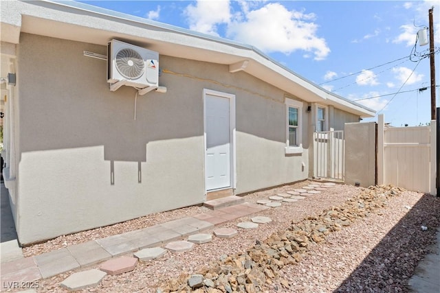 view of side of property featuring fence, stucco siding, and ac unit