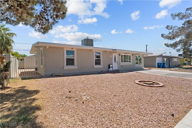 ranch-style house featuring cooling unit, stucco siding, and driveway