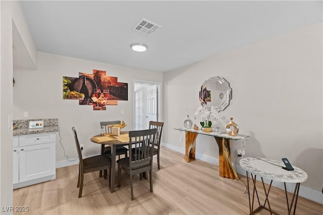 dining room featuring baseboards, light wood-style flooring, and visible vents